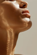 Close-up of radiant, bare skin with natural light and shadows highlighting smooth texture, representing the essence of skin minimalism and simplified skincare routines.